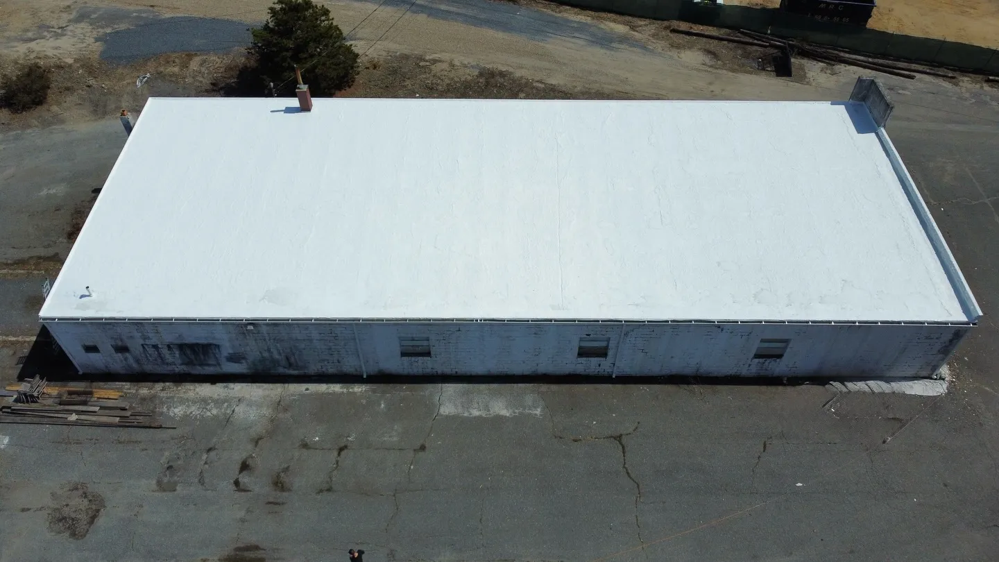 Aerial view of a large commercial building with a freshly coated white roof