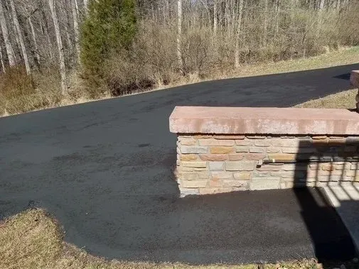 Freshly paved driveway with a stone wall.