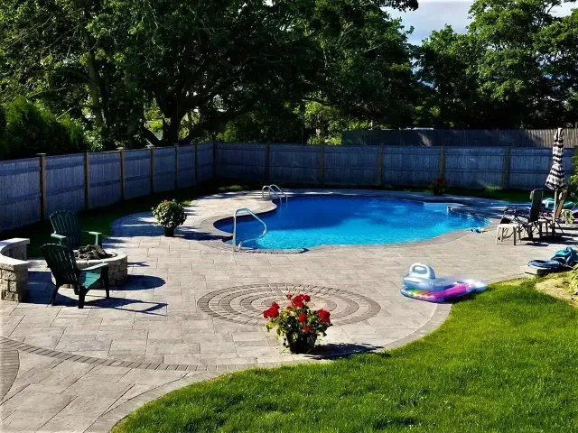A backyard patio with flagstone paving, a small patch of artificial grass, outdoor seating, and a privacy fence.