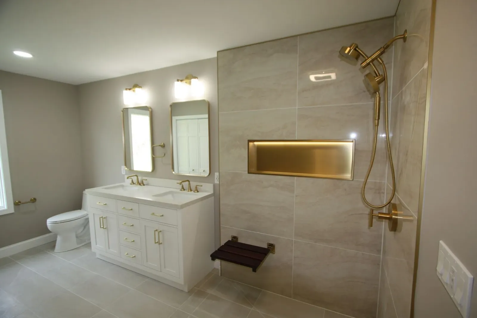 Modern accessible bathroom with double vanity, mirrors, walk-in shower, and beige tile walls