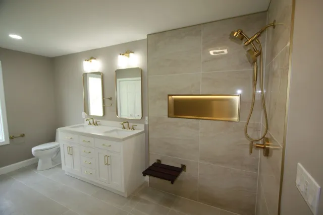 Modern accessible bathroom with double vanity, mirrors, walk-in shower, and beige tile walls