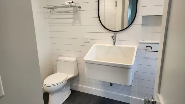 A bathroom with a toilet , sink and mirror.