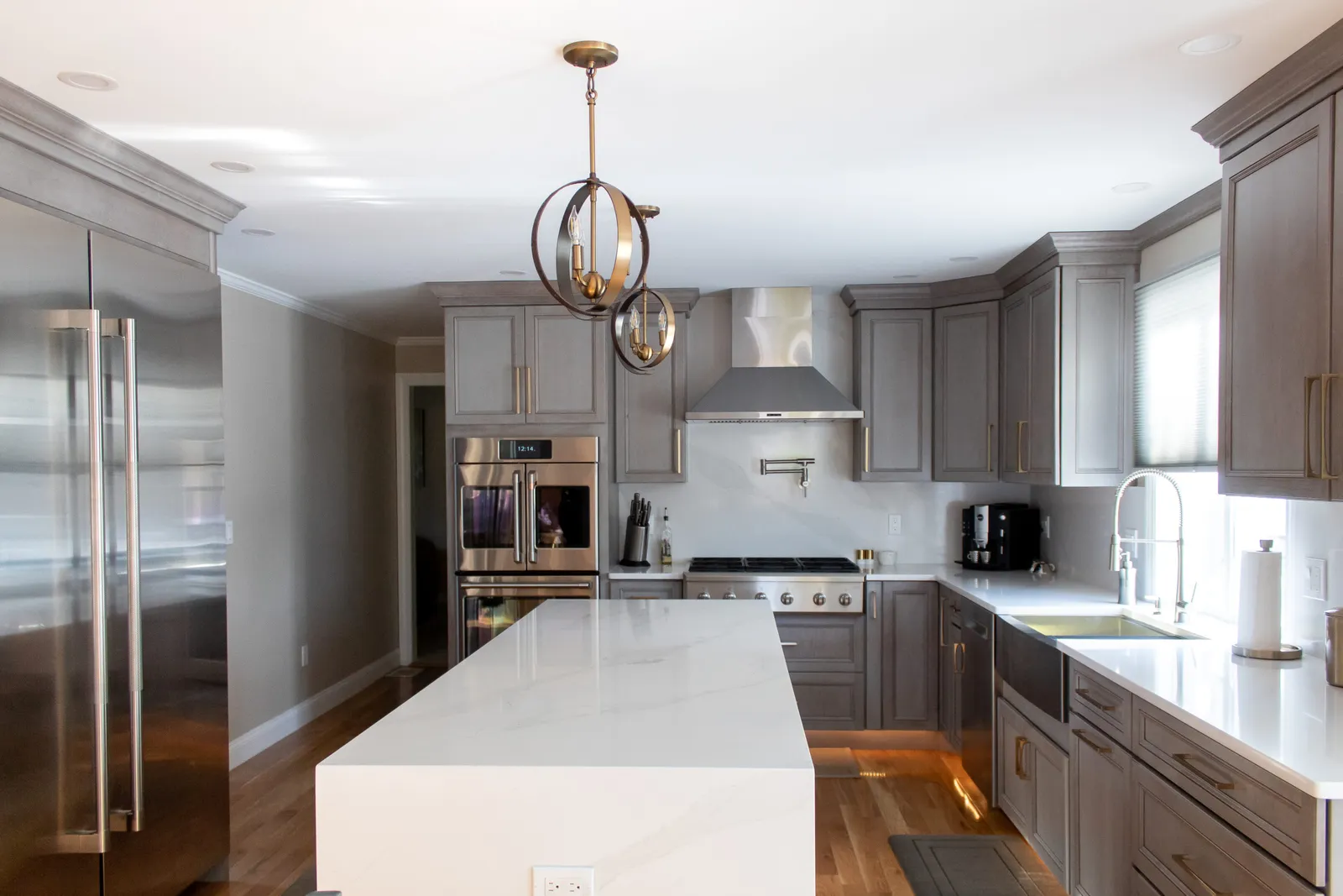 Grey kitchen with waterfall quartz island and glass pendants