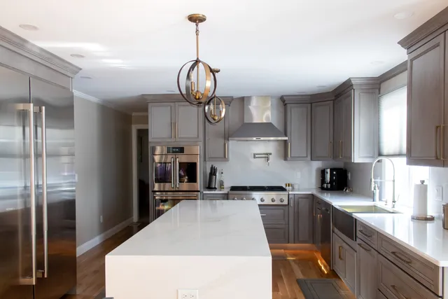 Grey kitchen with waterfall quartz island and glass pendants