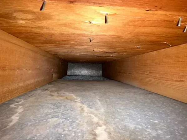 The same plywood air duct after cleaning - bare wood walls and floor, no dust left