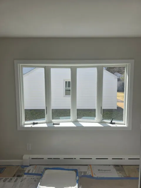 A large window in a room with a view of a white house.