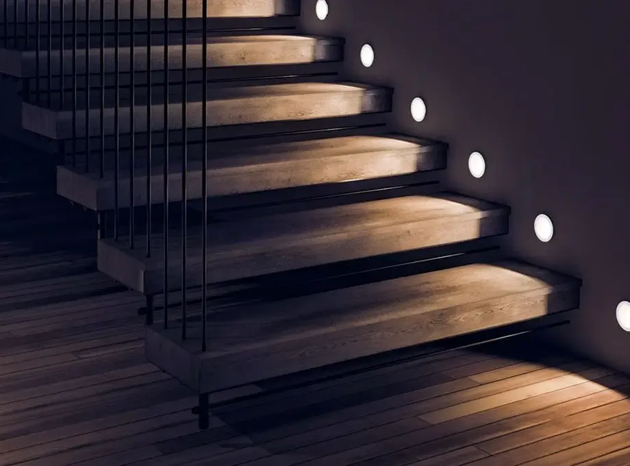Warm recessed LED step lights washing light across a modern wood staircase