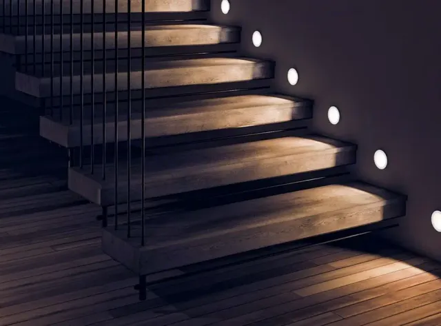 Warm recessed LED step lights washing light across a modern wood staircase