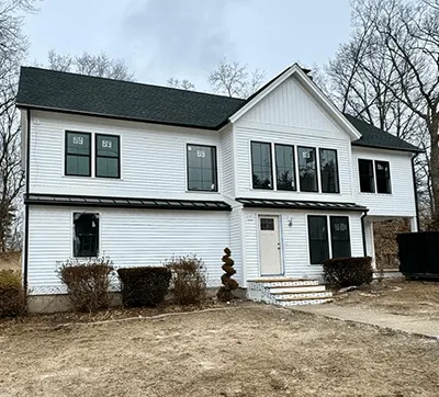A white two-story house with black shutters, numbered 59, on a barren landscape with a cloudy sky.