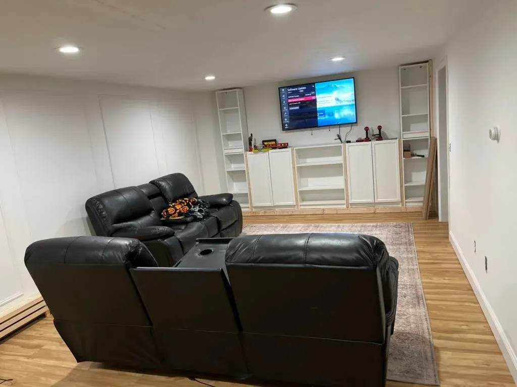 finished basement with LVP wood flooring, white walls, and built-in entertainment center