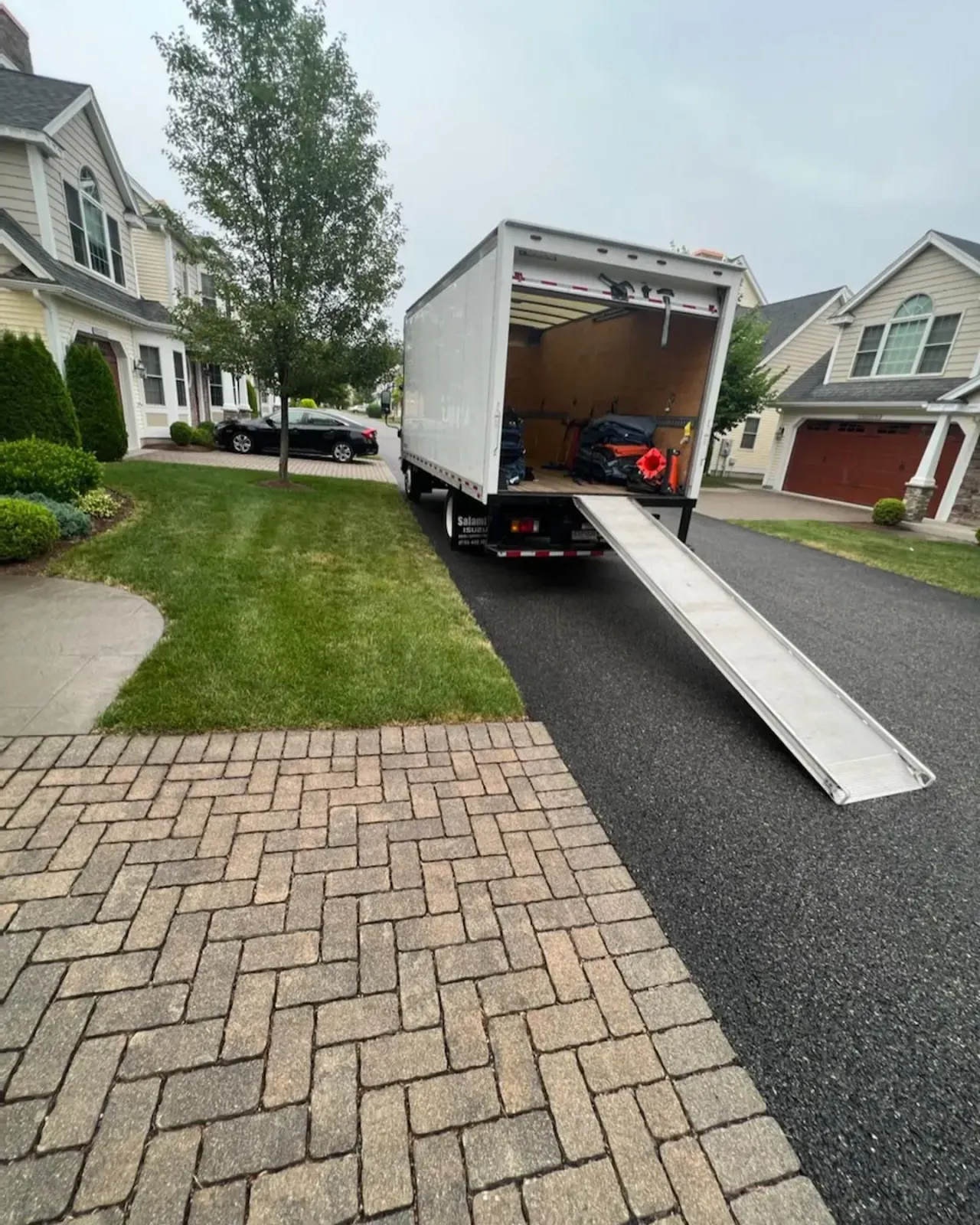 White moving truck parked on a residential street with ramp extended, ready for loading.