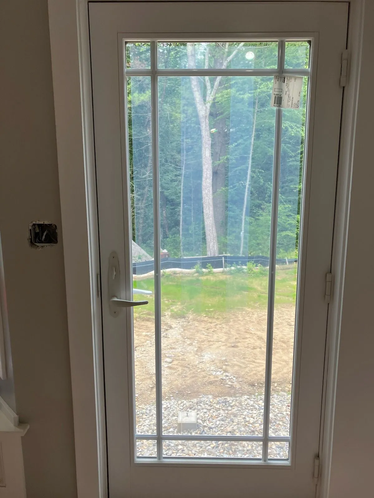 A white door with a view of a forest through it.