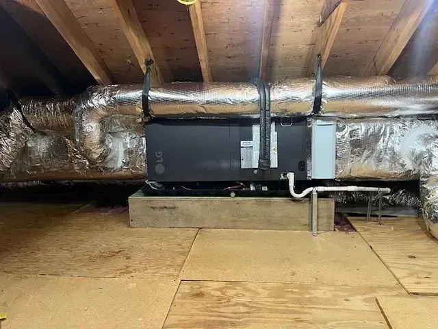 HVAC unit in an attic with insulated ducts and exposed wooden beams