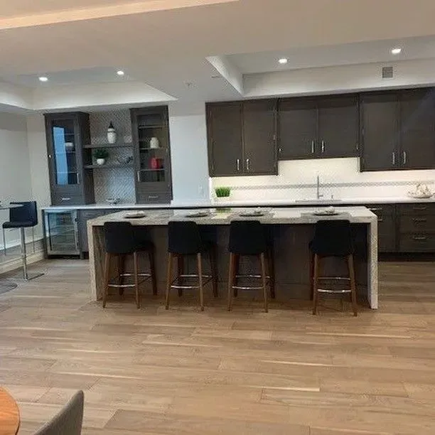a kitchen with a large island, stools, and cabinets