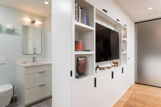 Modern living room with white built-in shelving, wall-mounted TV, and wood floor