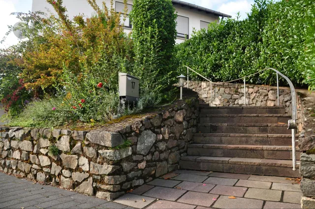 Weymouth, MA landscape construction featuring a natural stone retaining wall, stone steps, and integrated plantings by JRD Landscape Design.