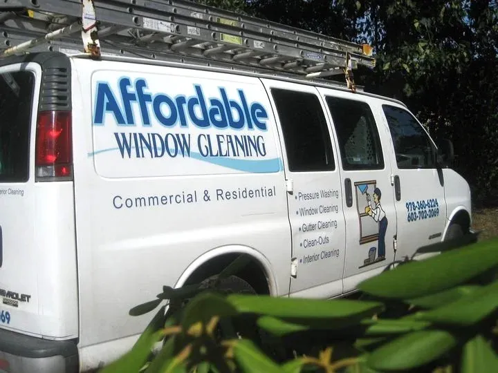 White van with "Affordable Window Cleaning" logo and services list, including pressure washing, window cleaning, and gutter cleaning. Ladder on the roof. Partial contact numbers visible.