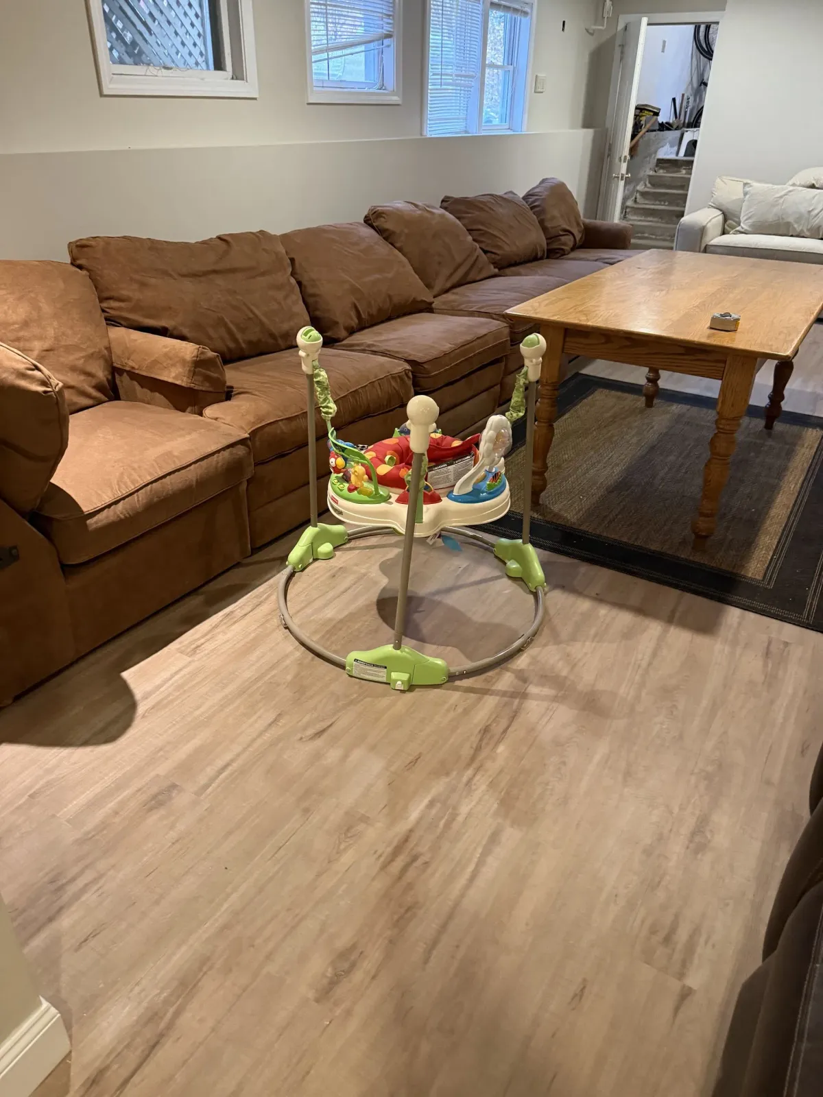 A baby walker is sitting on a wooden table in a living room.