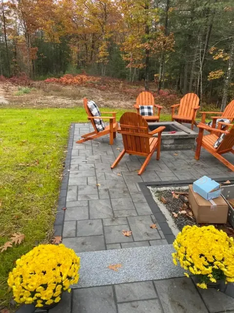 A patio with chairs and a fire pit in the middle of it.