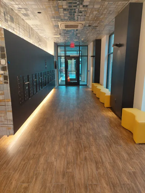 Long hallway with dark wall, yellow benches, and exit door.