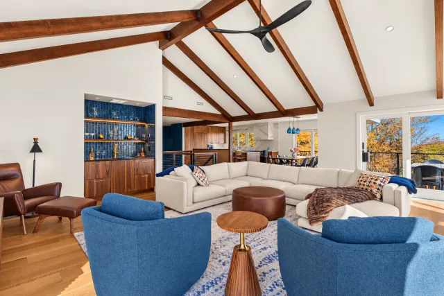 Quechee living room with blue chairs, pale sofas and exposed ceiling beams.