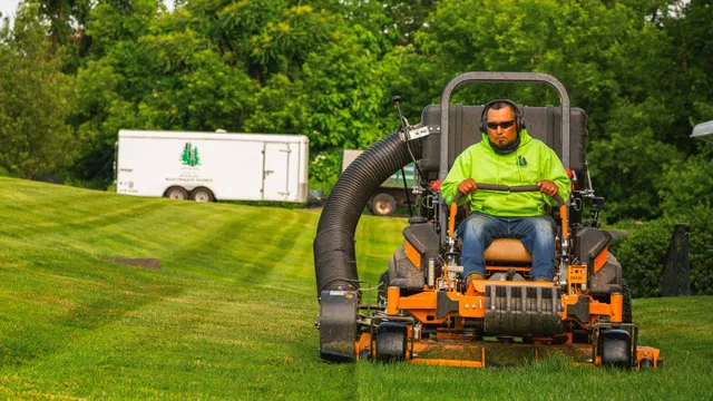 Man in green hoodie and sunglasses operating an orange lawn mower on grass near trees.