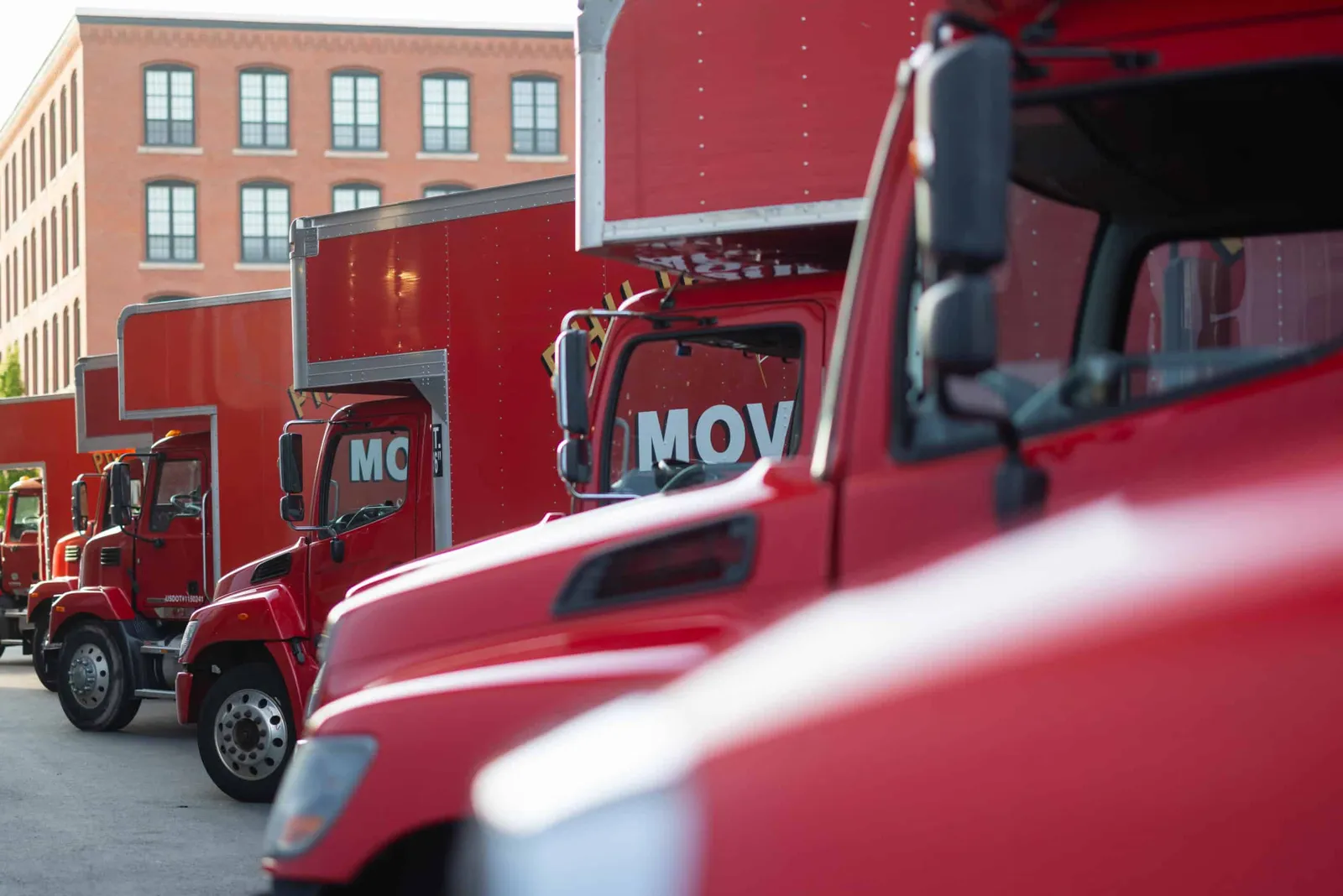 A row of red trucks parked in front of a building.