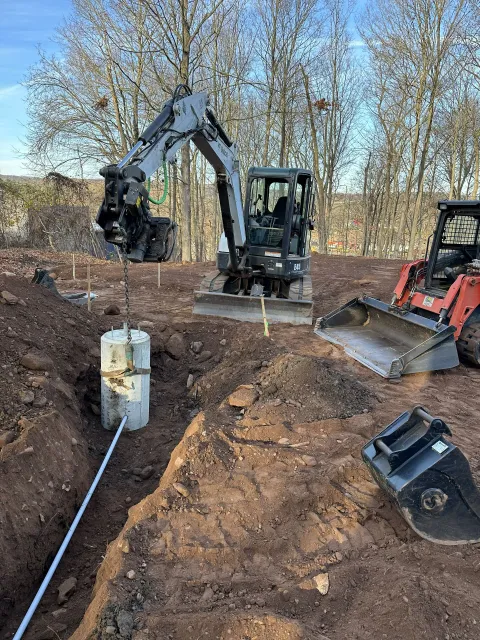 Construction site with excavator and small loader, digging in brown soil.