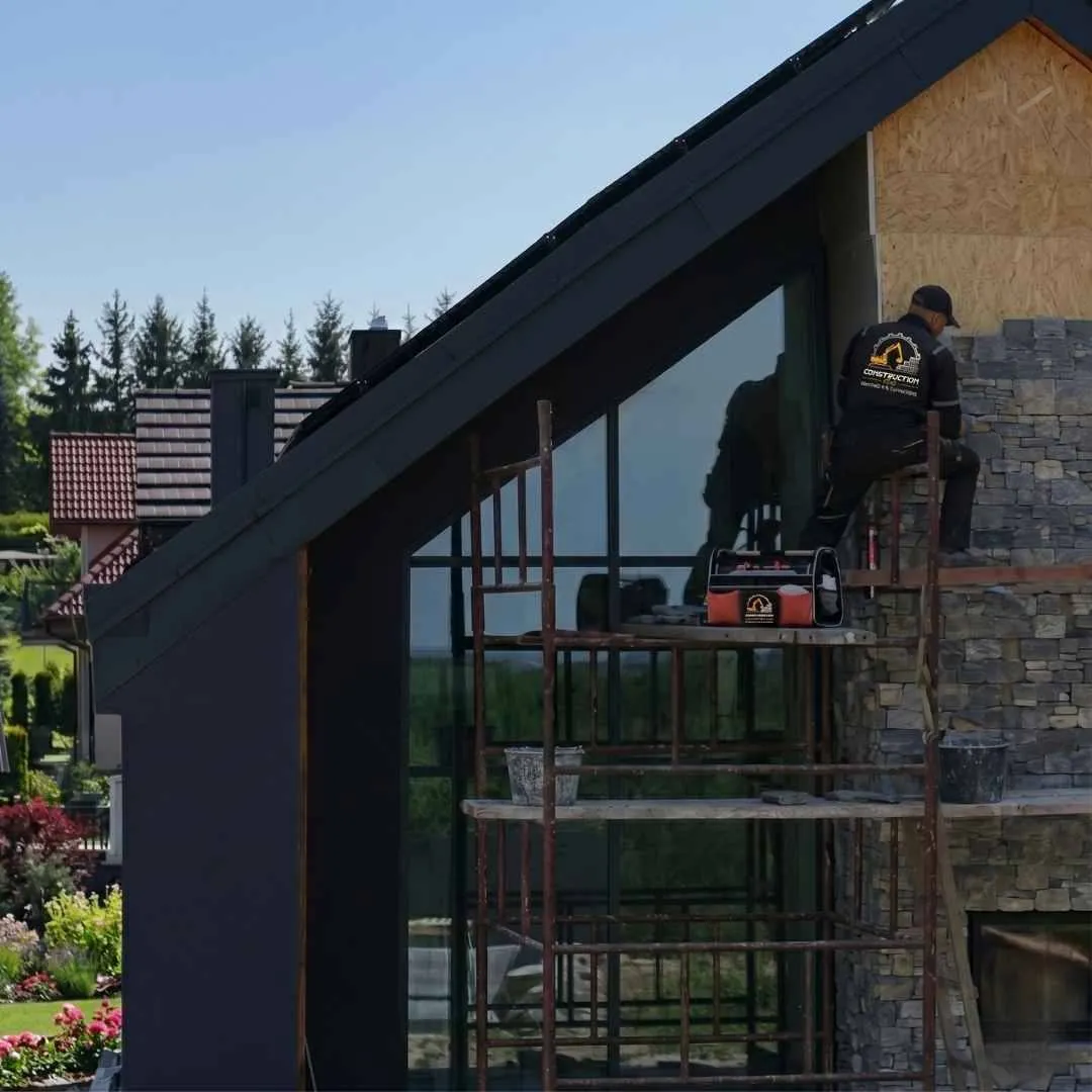 Construction 10X worker laying stone on residential house facade