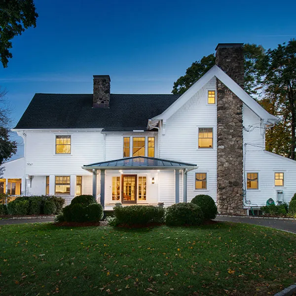 White remodeled residence with a steep dark roof and stone chimney