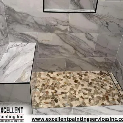 A shower stall with marble tiles and a pebble floor.