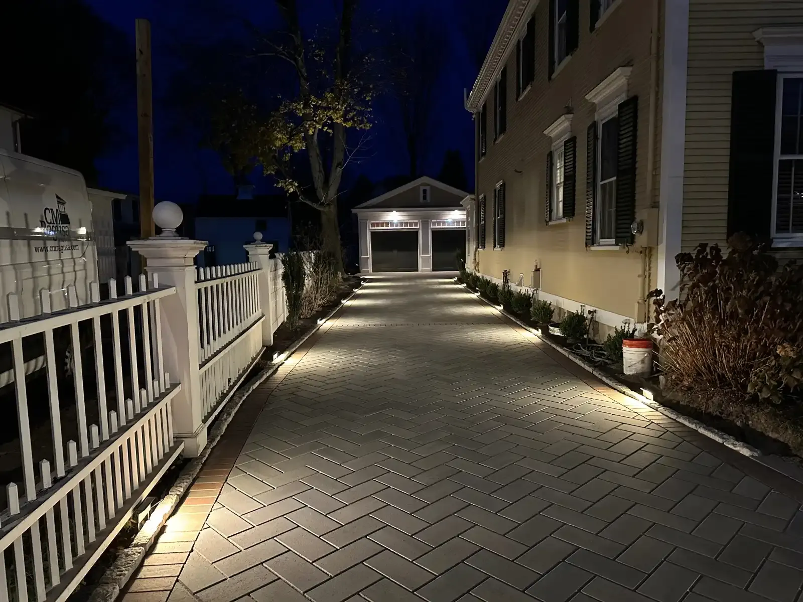 Paver driveway lit by low voltage landscape lighting