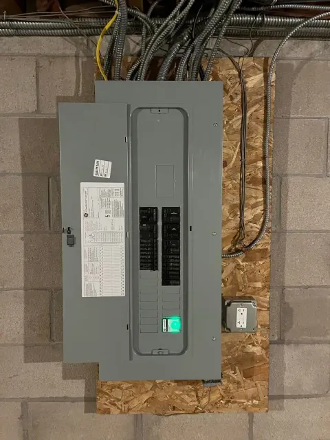 A electrical box is hanging on a brick wall.
