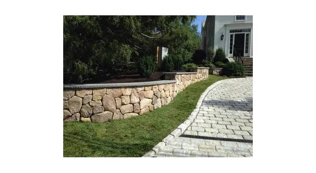 Finished driveway bordered by a natural stone retaining wall
