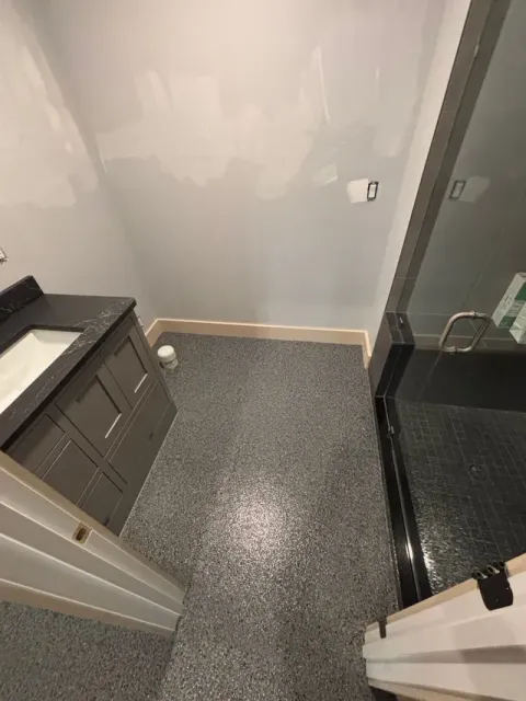 Bathroom with gray epoxy floor, gray vanity, and glass shower.