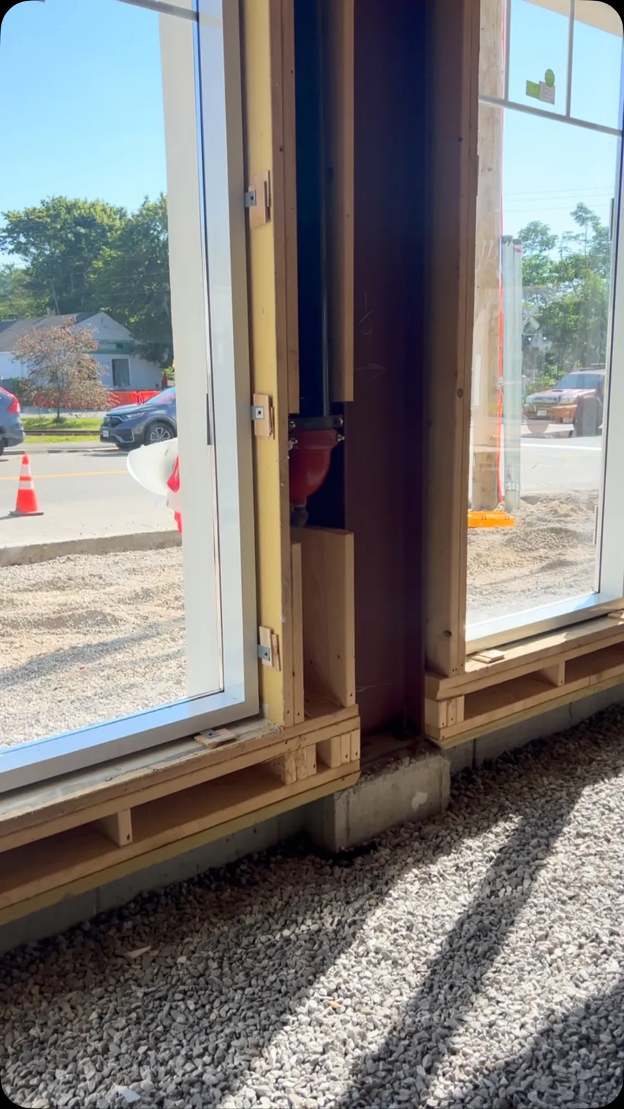 Instead of drilling through the aluminum curtain wall frame, we use metal straps fastened to the exterior of the frame. Once the wall is shimmed and aligned, the straps are secured to the surrounding framing. This keeps screws out of the aluminum, creates a cleaner finish, and allows the drywall to cover the straps for a seamless appearance.