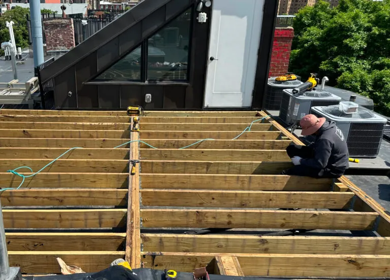 Contractor installing deck framing and joists during exterior construction in Boston, MA.