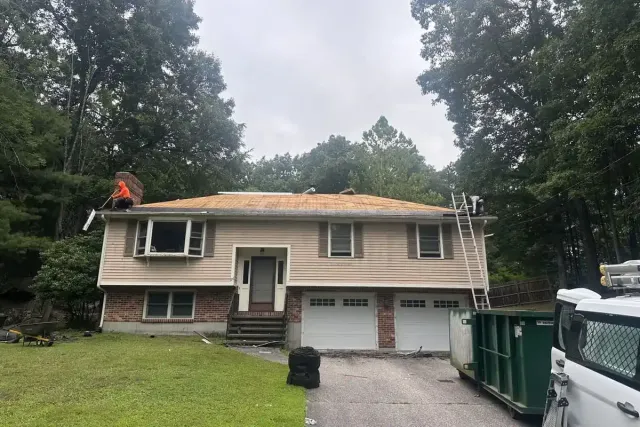 Roofing crew performing a multi-layer shingle tear-off on a split-level home in Salem NH