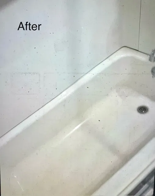 Clean, white bathtub after cleaning. Corner setting, with drain visible.