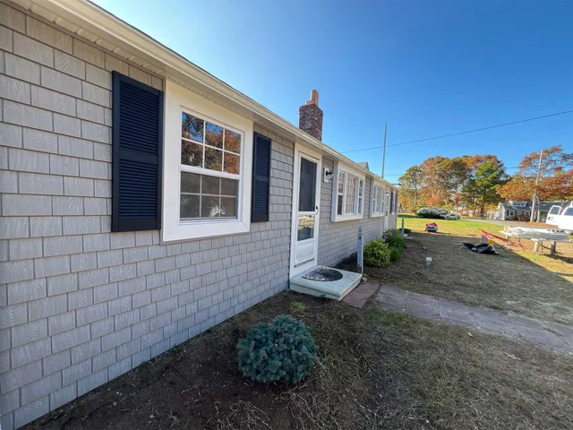 Home exterior with gray shake siding, white trim, black shutters, and entry door
