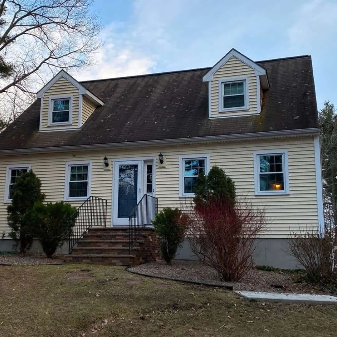 Yellow-two-story-house-with-shingled-roof,-dormer-windows,-and-blue-front-door