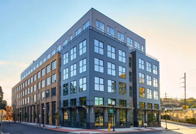 Modern mixed-use building with brick façade — street-level view of a six-story development featuring retail at the ground floor and residential units above.