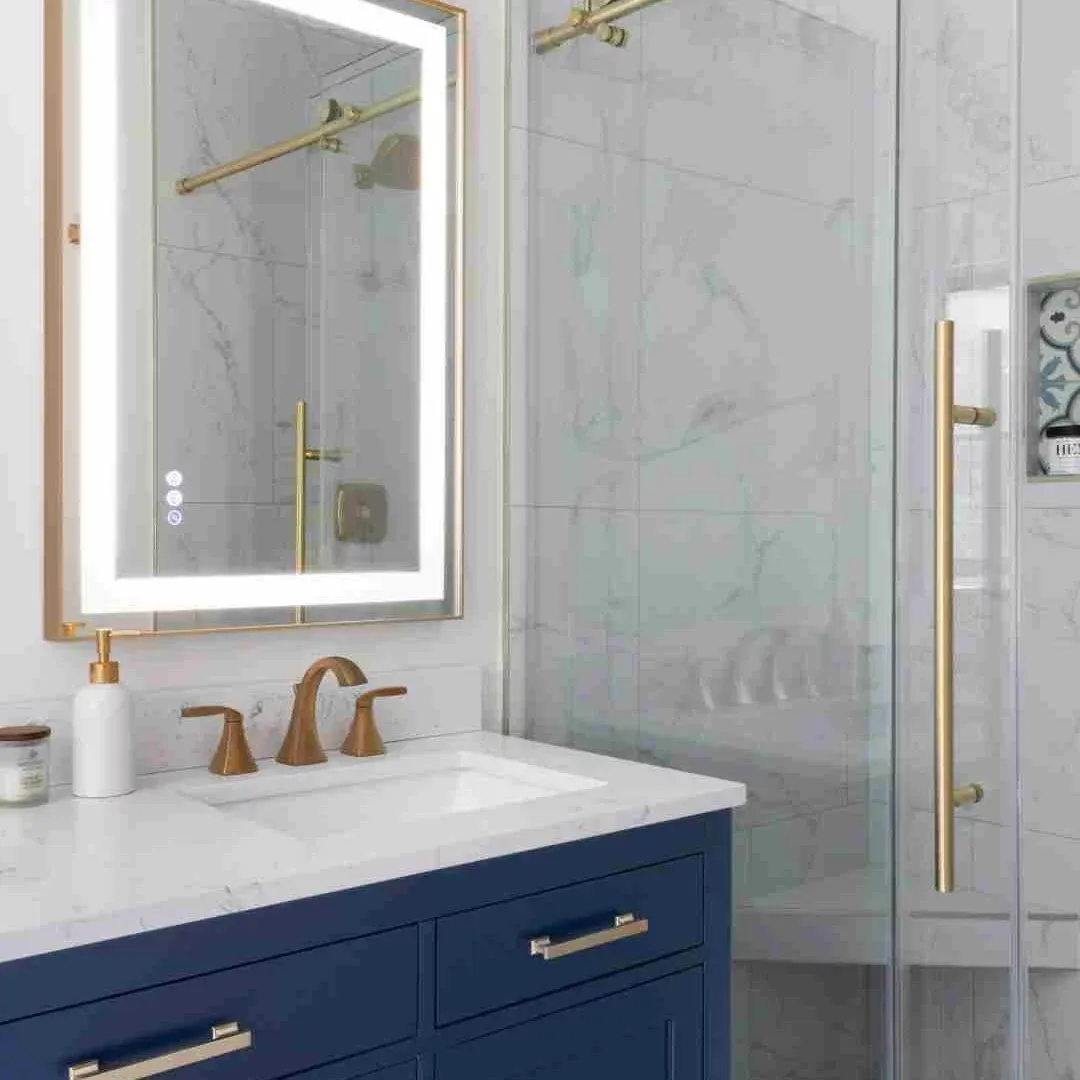 A modern bathroom with blue cabinetry and a luxurious gold sink, showcasing elegant design elements.