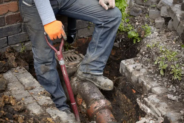 A person with an orange glove is digging a hole.