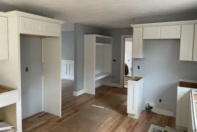 Unfinished interior room with white built-in cabinetry and light gray walls under construction.