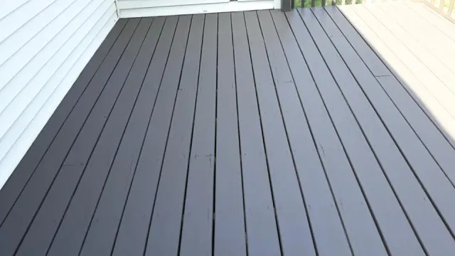 A black wooden deck with a white house in the background.