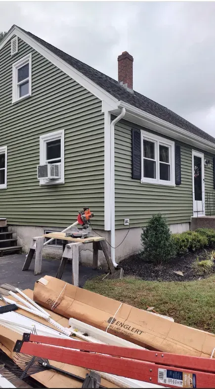 A green house with a ladder in front of it.