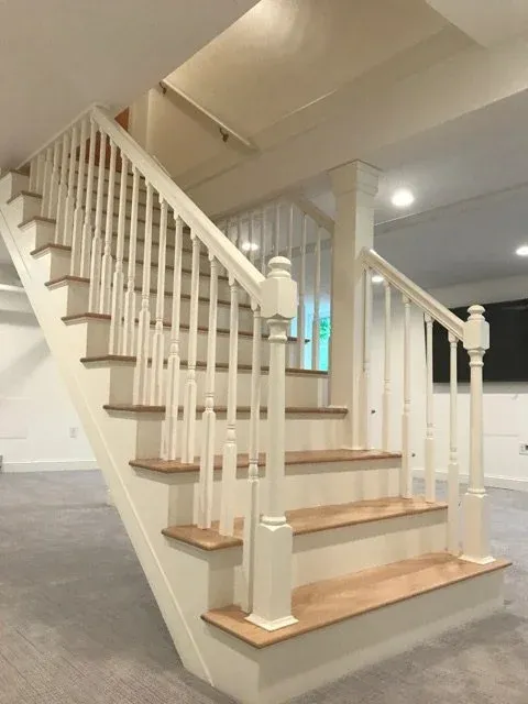 Interior view of a staircase with white banisters and wooden steps in a modern home.