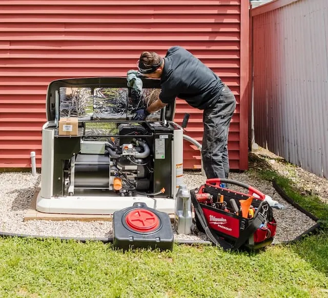 Man servicing a Generac home generator with a tool bag nearby.