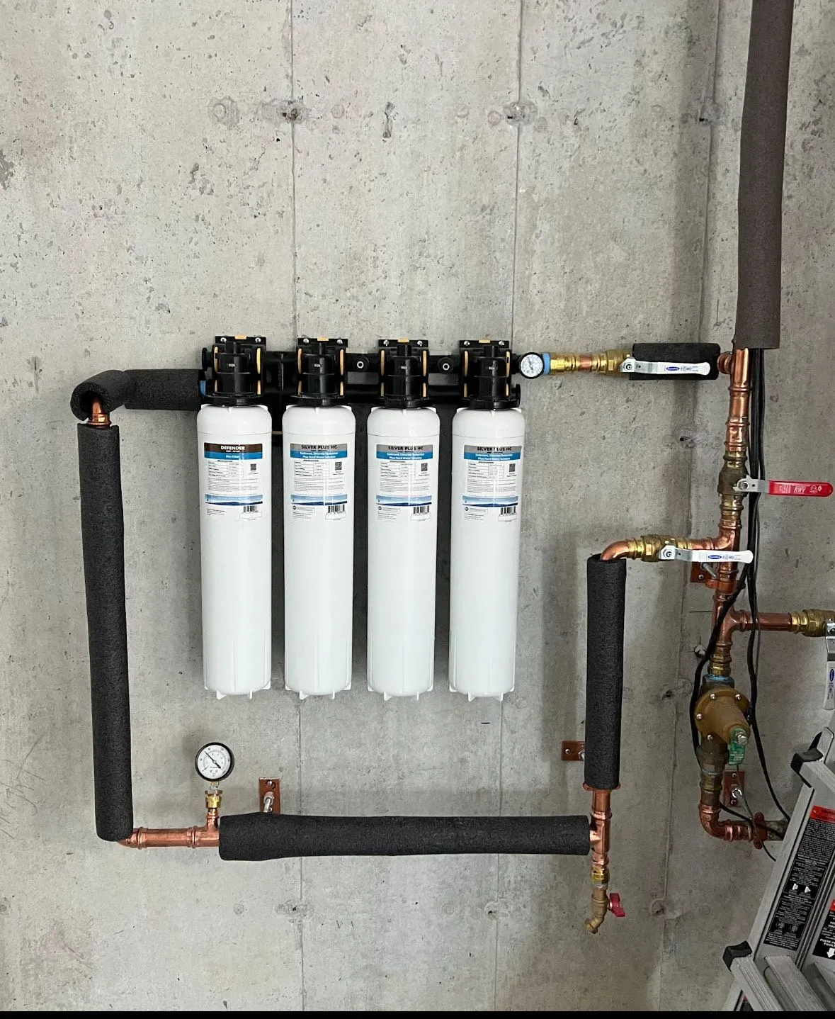 A water filter system is installed on a concrete wall